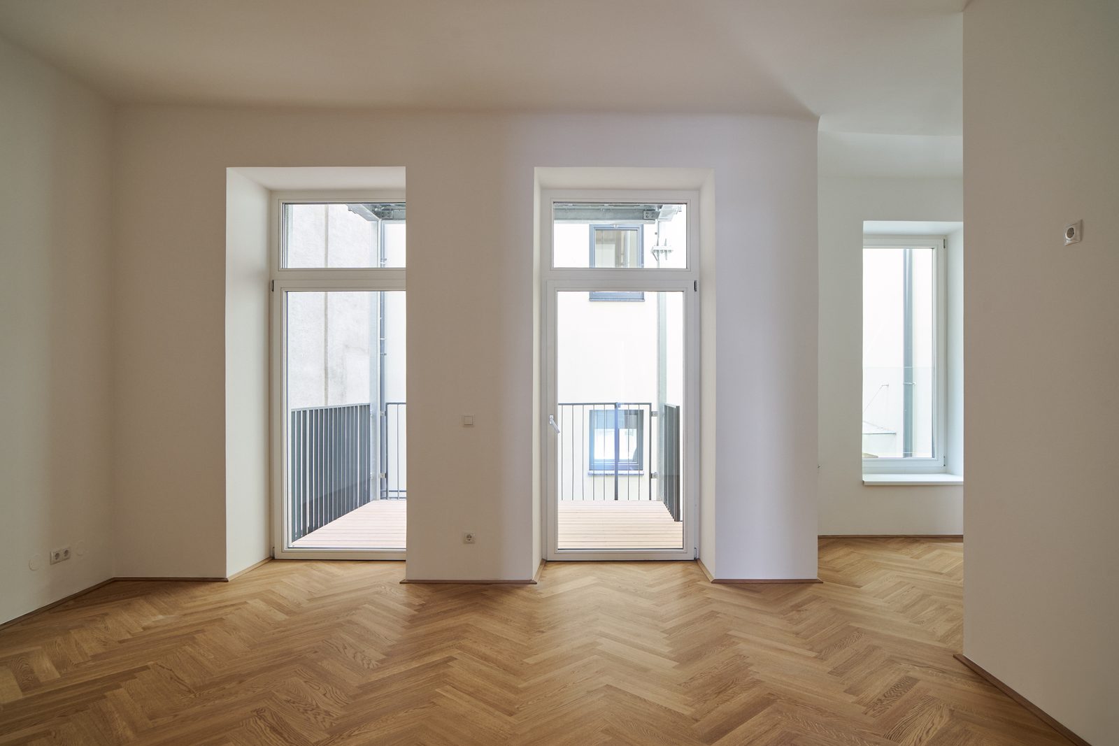Heller Wohnraum mit zwei Balkontüren und Fischgrätparkett, Meiselstraße 9