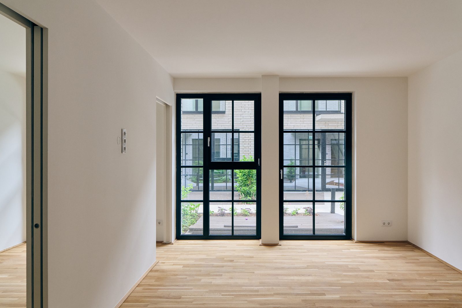 Wohnraum mit zwei Stahlfenstern zum Innenhof, Eichenparkett