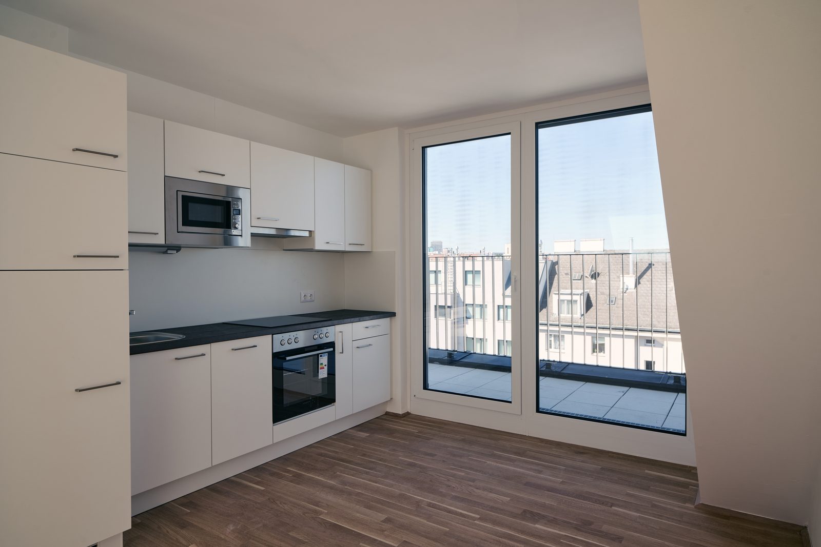Küche einer Dachgeschoßwohnung mit großer Fensterfront über den Dächern