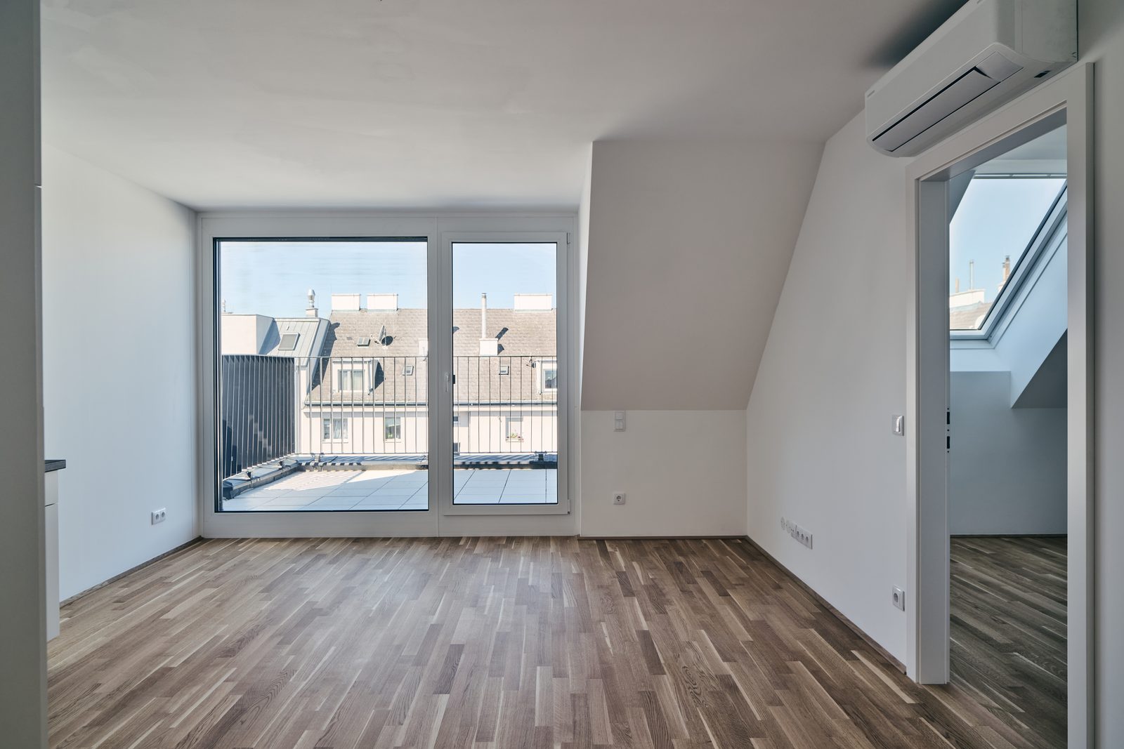 Zimmer im Dachgeschoß mit Terrassentür und Blick über die Dächer von Favoriten